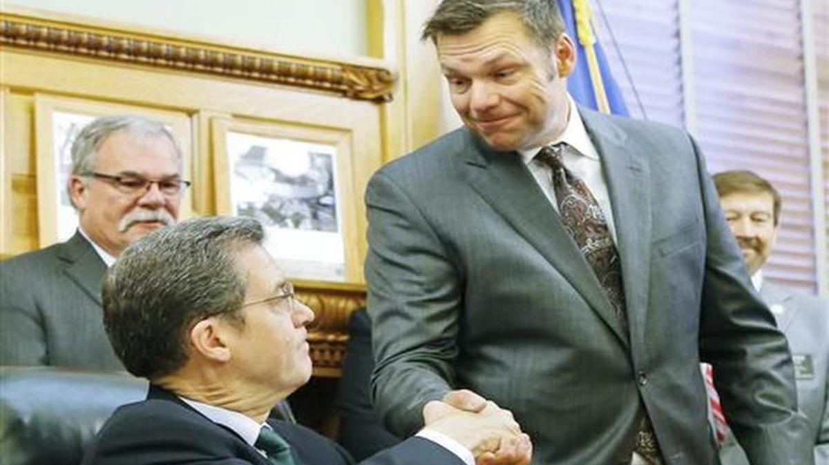 Kansas Secretary of State Kris Kobach, right, shakes hands with Gov. Sam Brownback on June 8, 2015, at a bill-signing ceremony giving the secretary authority to prosecute election crimes. Now a state legislator has filed a bill to revoke that authority.
