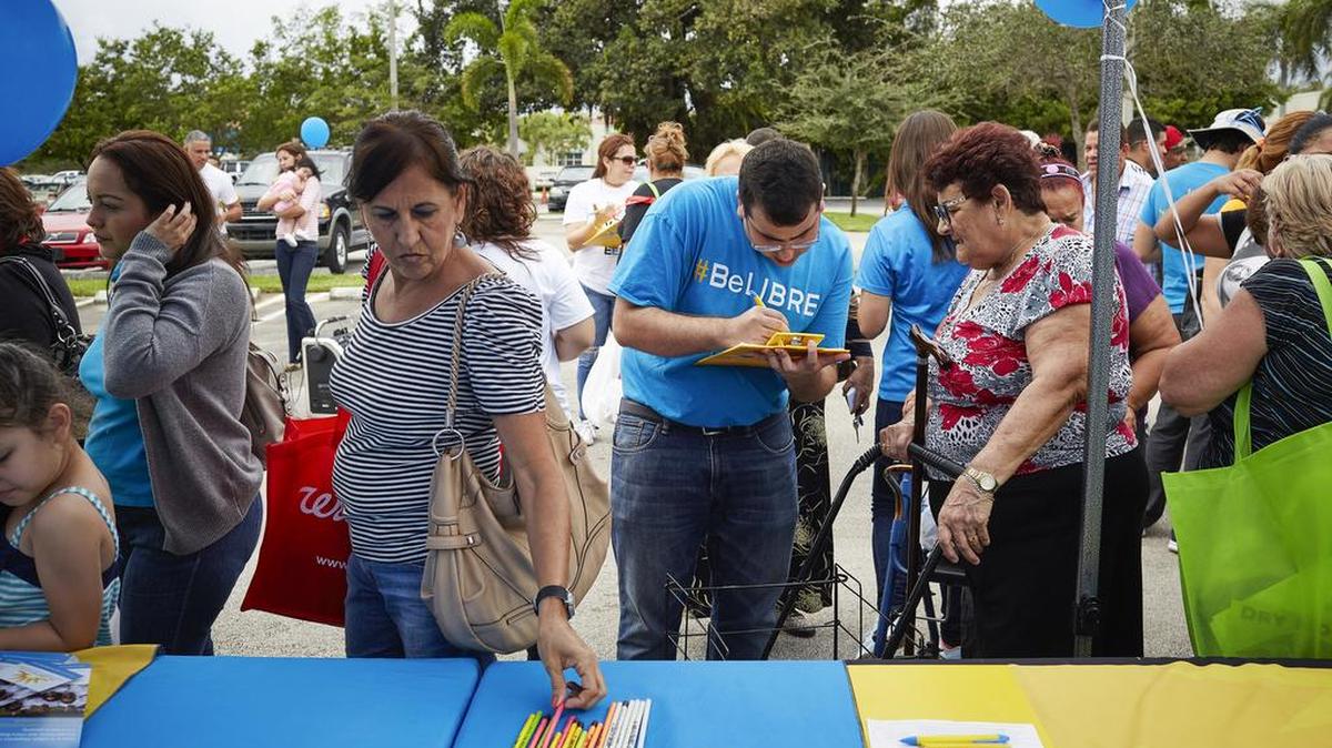 A volunteer for the Libre Initiative collects information from a member of the crowd that turned up for free health screenings and turkeys at the Alpha Omega church in Miami on Nov. 21. Libre, a multimillion-dollar effort financed by the conservative billionaire Koch brothers, is devoted to winning over Hispanics with the message that economic freedom and smaller-government principles will yield opportunity and prosperity.