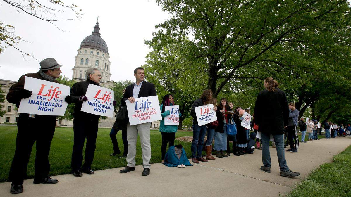 About 100 anti-abortion demonstrators, including former Kansas Secretary of State Kris Kobach (third from left), protest across the street from the Kansas Supreme Court building in Topeka last May.