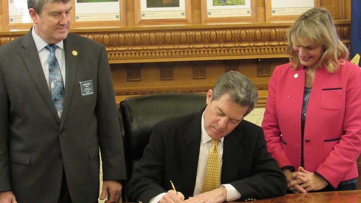 Gov. Sam Brownback signs a bill fixing timing requirements for a special congressional election. He is joined by Rep. Keith Esau, R-Olathe, and Sen. Elaine Bowers, R-Concordia, the chairs of the election committees.