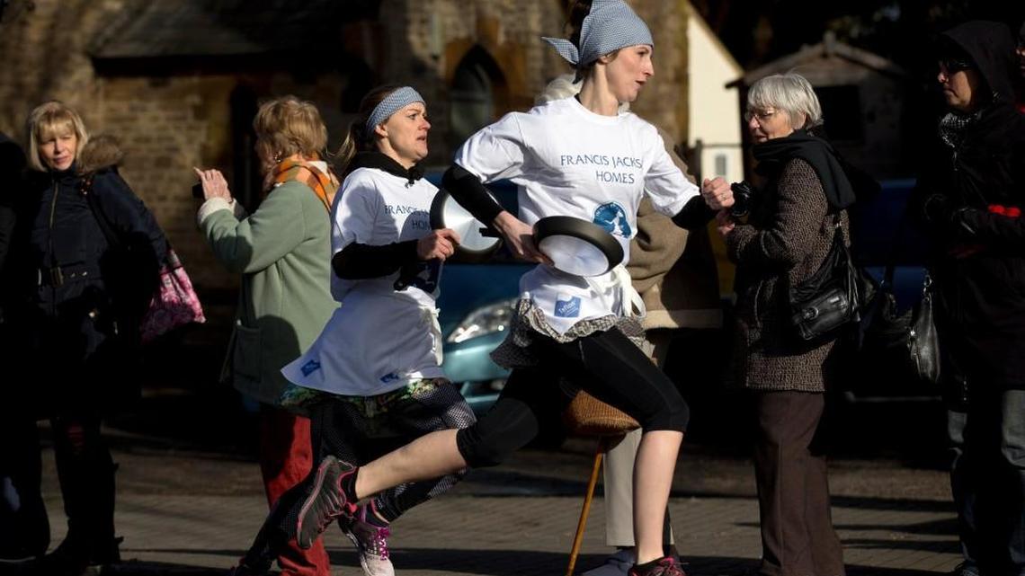 First place finisher Lianne Fisher, right, pulls away from second place finisher Kaisa Larkas, en route to setting a course record time of 55.02 seconds during the annual Shrove Tuesday trans-Atlantic pancake race in the town of Olney, in Buckinghamshire, England, Tuesday, Feb. 9, 2016.