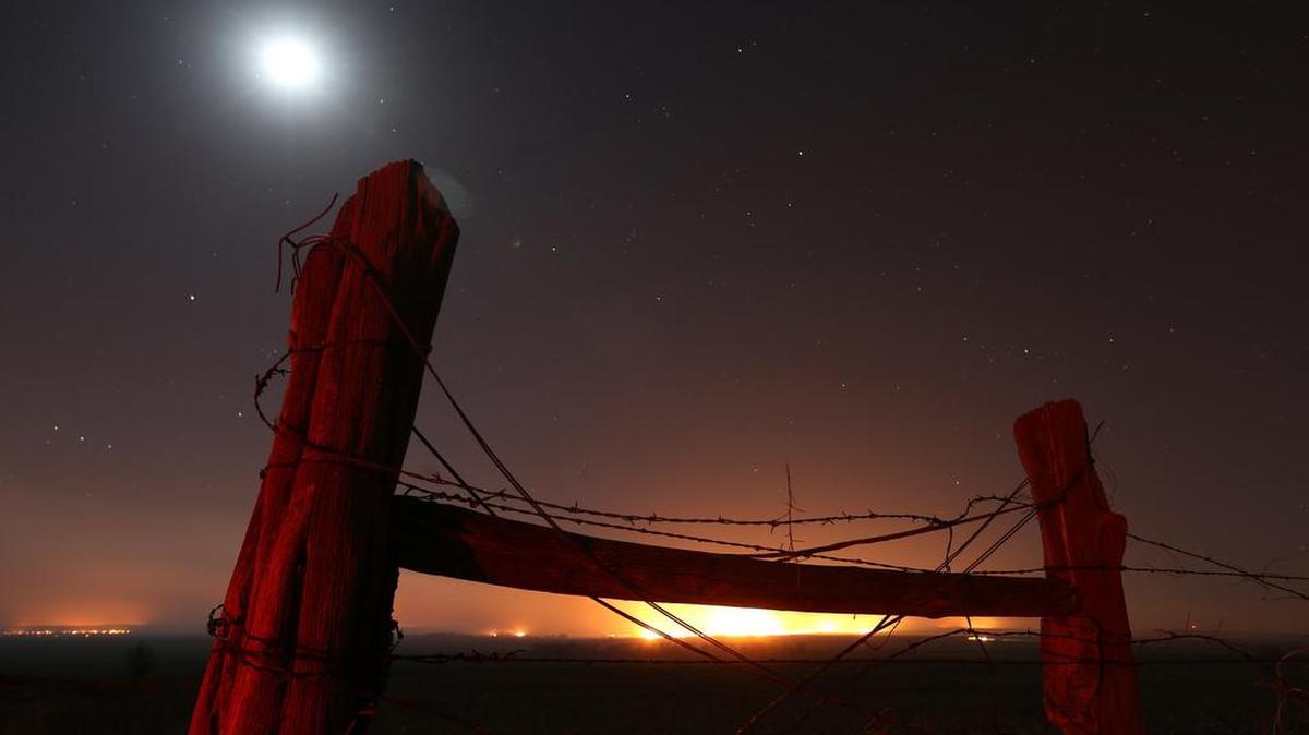 The moon and stars frame the orange glow of a huge wildfire in southern Kansas on Monday night. More than 502,000 acres have burned in Clark and Comanche counties over the past few days, making it the most widespread single fire on record for the state.