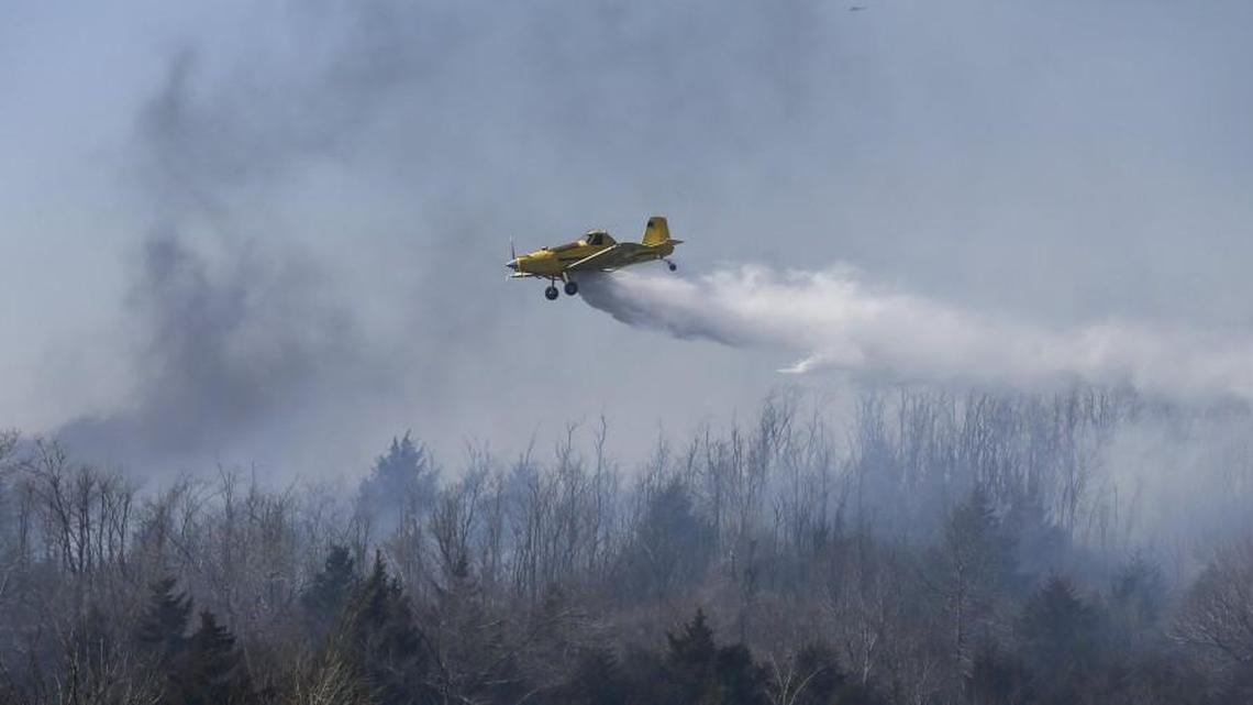 A crop duster drops water on a wildfire along K-61 just north of Hutchinson. An “after action” report will look critically at what lessons can be learned from the recent wildfires and possibly make determinations about what resources to have on call during high-risk periods.