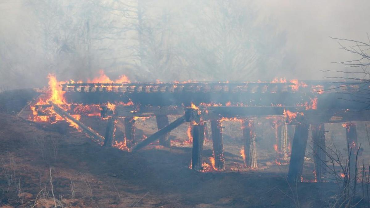 A old train trestle bridge burns near Lake City, Wednesday, March 23, 2016. The bridge was set afire by a large grass fire burning in Barber County.