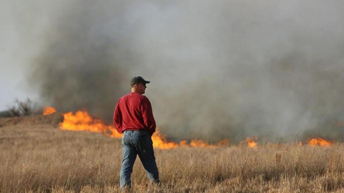 John Wildin watches as a wildfire burns Sunday in Hutchinson. Interim Hutchinson Fire Department Chief Doug Hanen says fire crews are working to control numerous hot spots in the fire.