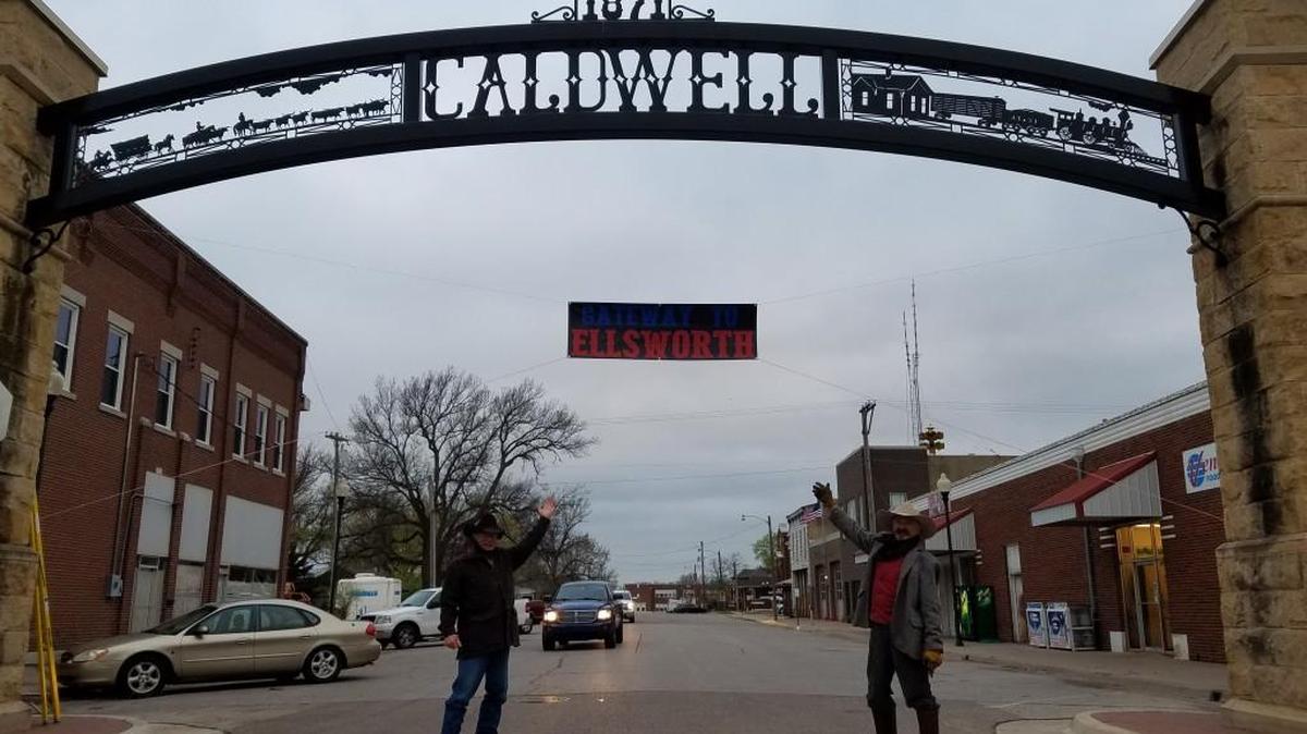 A banner strung below the city of Caldwell’s arch says “Gateway to Ellsworth.” Dennis Katzenmeier, left, and Jim Gray were playing an April Fools’ Day/Chisholm Trail joke.