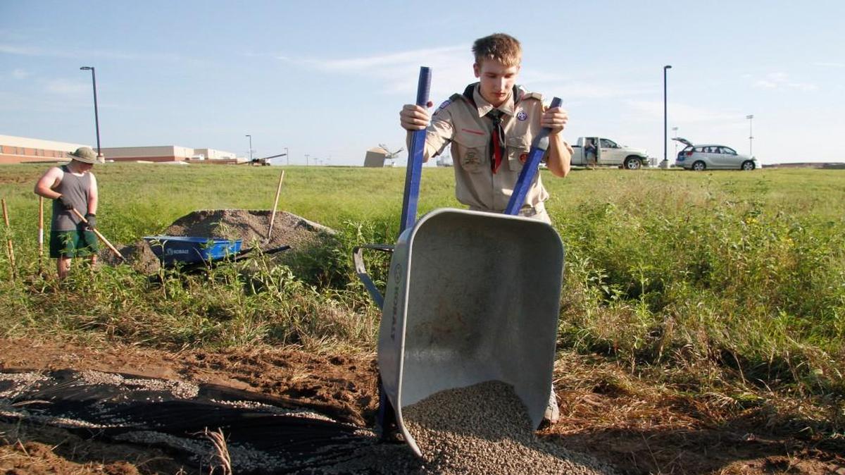 Kyle Stutzman dumps a load of gravel on a hiking trail he is improving as part of his Eagle Scout project, near Eisenhower High School, in Goddard.