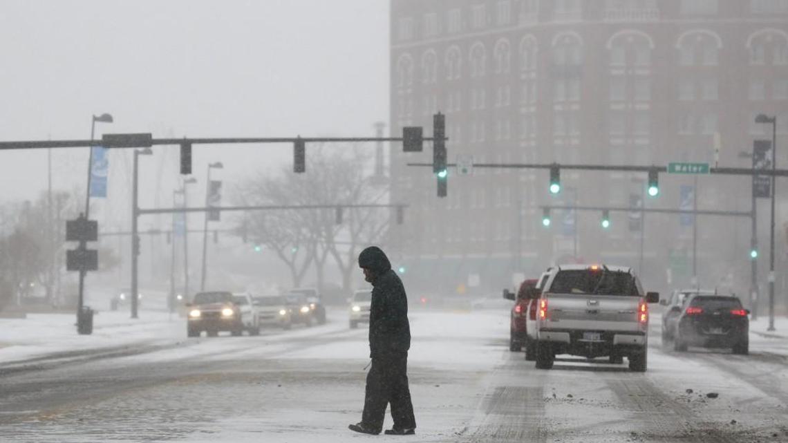 A pedestrian crosses Douglas in downtown Wichita on a snowy day in December 2016.