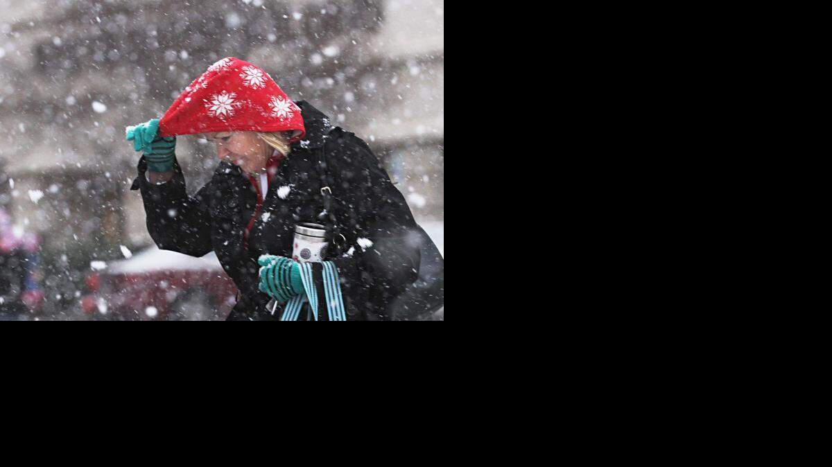 
A downtown Wichita pedestrian takes cover from a late Wednesday afternoon snowfall that produced large flakes and quickly accumulated on streets and cars. 
