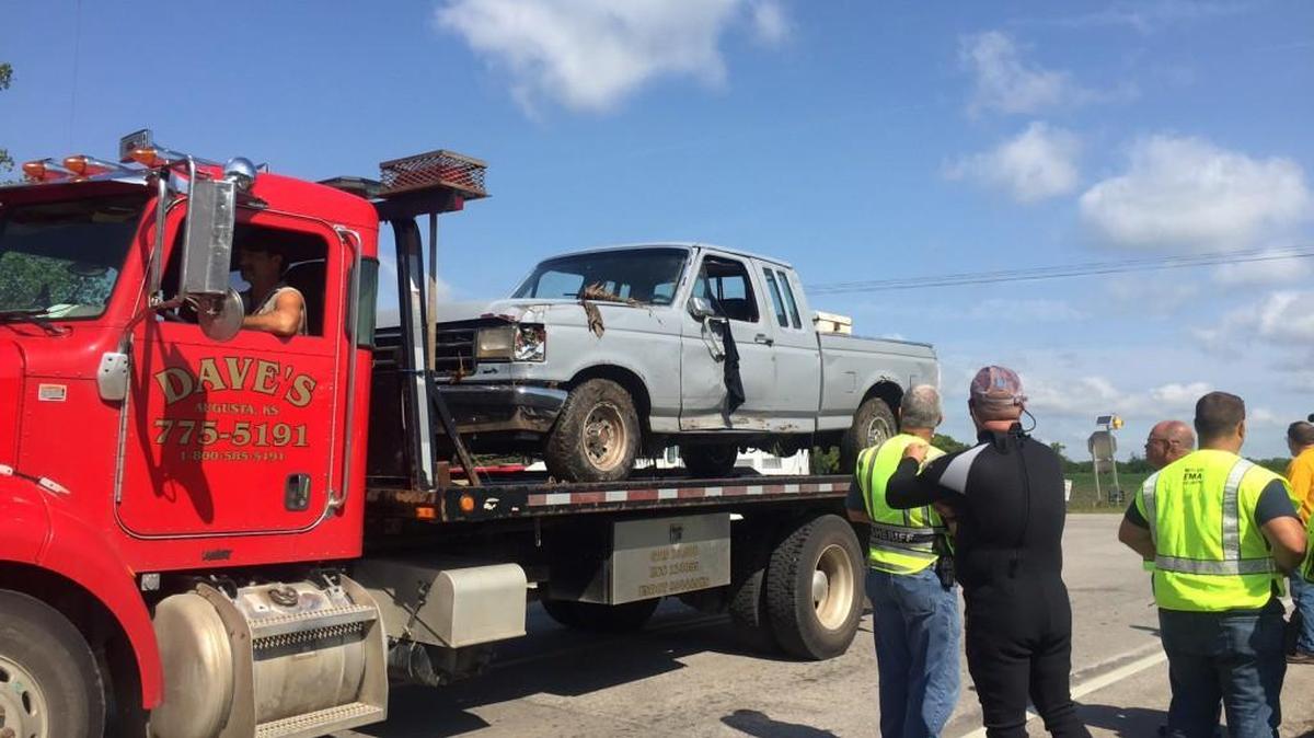 Searchers from Butler County, Augusta and Rose Hill look on as the truck of a Wichita man missing in a flash flood is hauled away from the creek near Southwest 210th and Butler roads.