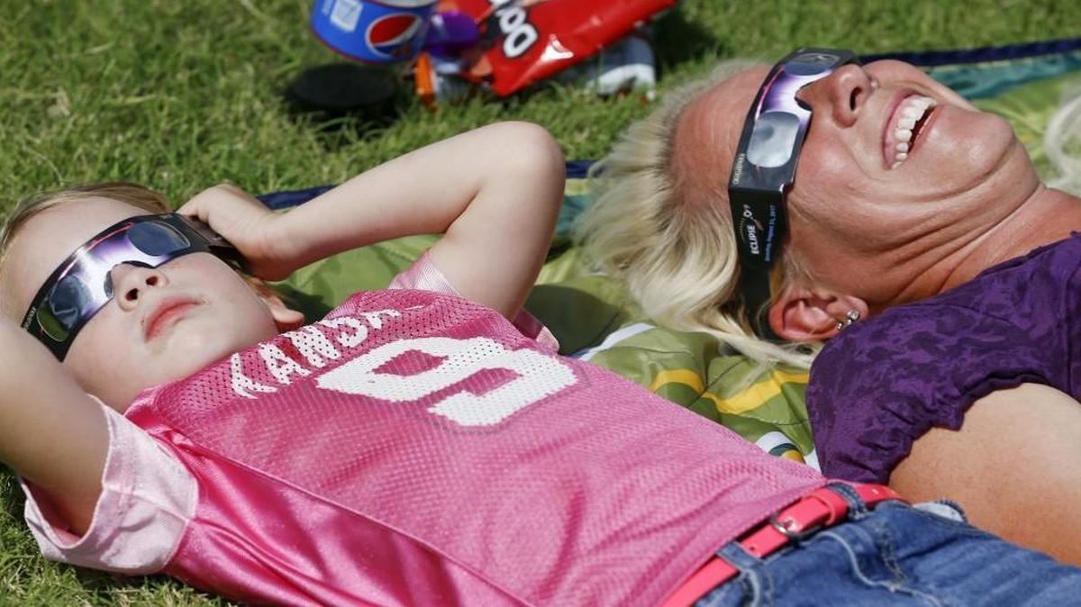 Debra Hamilton, right, and her daughter Chloe, 4, take a look at the sun during the eclipse at Exploration Place on Monday.
