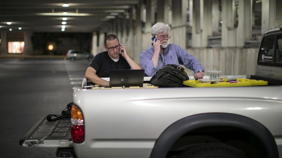 Staff photographer Josh McKerrow, left, and staff reporter Pat Furgurson work on Friday’s edition of The Capital in a parking garage in Annapolis, Md., on Thursday.