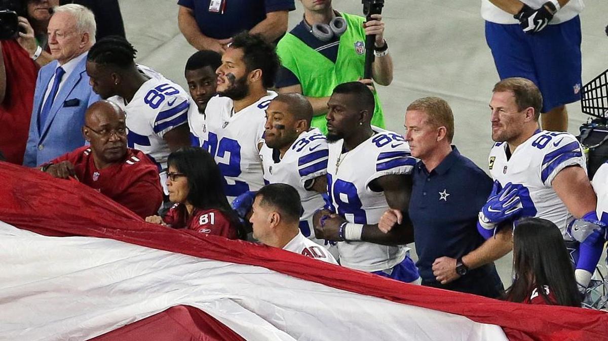 Dallas Cowboys owner Jerry Jones, left, and head coach Jason Garrett, second from right, stand with their players for the national anthem prior to an NFL football game against the Arizona Cardinals in Glendale, Ariz., on Sept. 25. Dak Prescott, Dez Bryant and the rest of the Cowboys have stood for every national anthem since the kneeling controversy started. But after their bye week, they did it for the first time since owner Jerry Jones publicly threatened to bench any player who in his view disrespected the flag.