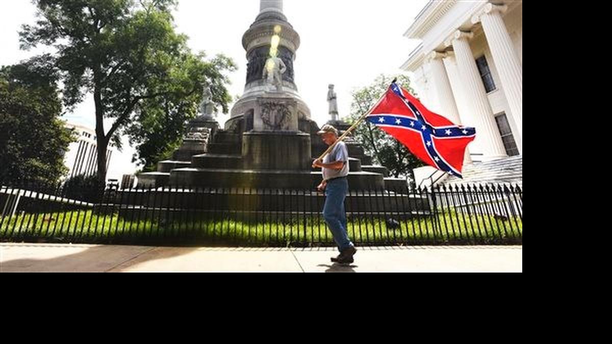 
A man carries a Confederate flag past the Confederate Monument on the Capitol grounds in Montgomery, Ala., after four flags were removed.
