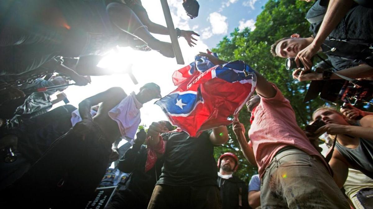 Counter-protesters tear a Confederate flag during a white nationalist rally Saturday in Charlottesville, Va. The deadly white nationalist demonstration in Virginia has brought new attention to an anti-fascist movement whose black-clad, bandana-wearing members have been a regular presence at protests around the country in the last year. Members of the antifa movement were among those protesting the Charlottesville rally last weekend.