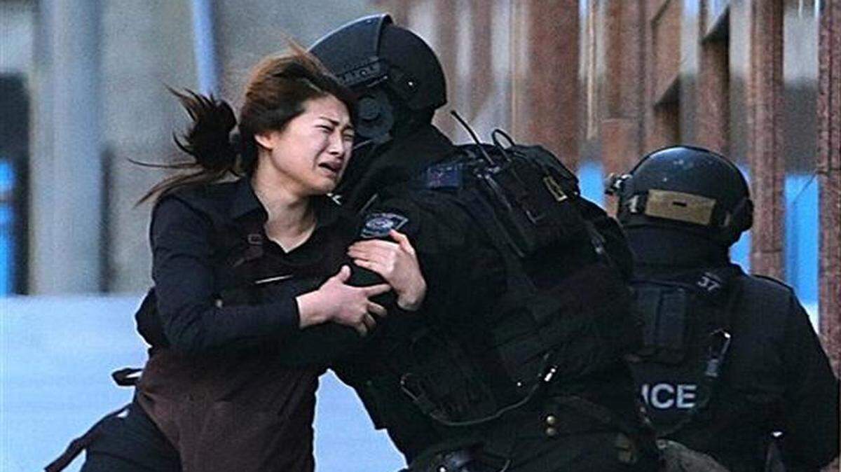 
A hostage runs to armed tactical response police officers after escaping from a cafe under siege in Sydney, Australia.
