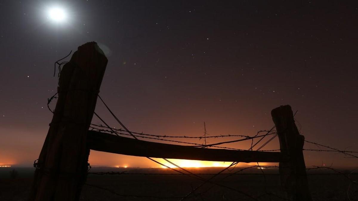 The moon and stars frame the orange glow of a huge wildfire in southern Kansas in March. Wildfires swept by high winds threatened numerous towns.