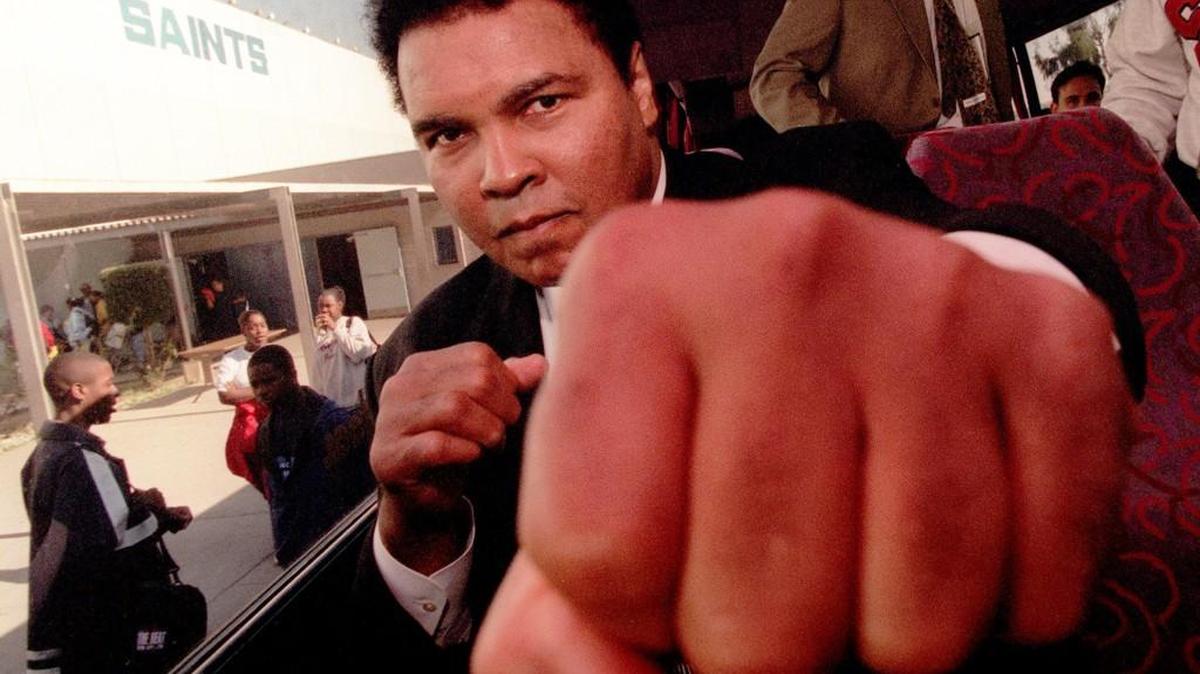 Muhammad Ali throws a playful punch toward a photographer while visiting Locke High School in Los Angeles on Dec. 4, 1996. Muhammad Ali died on Friday, June 3, 2016, at 74.