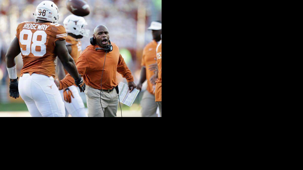 
Texas Longhorns coach Charlie Strong, right, congratulates players as they walk off the field after a game against West Virginia. 
