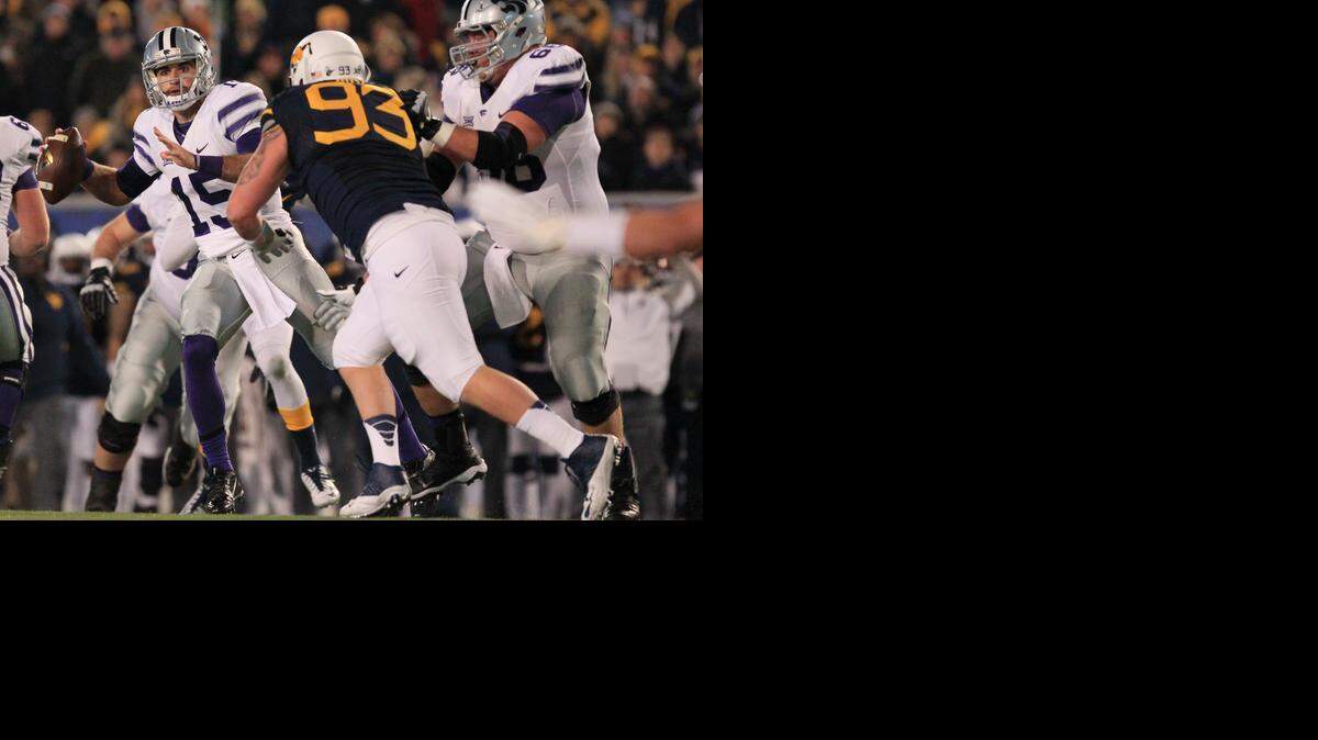
Kansas State quarterback Jake Waters looks for an open receiver as West Virginia's Kyle Rose (93) closes in on him during the first half.
