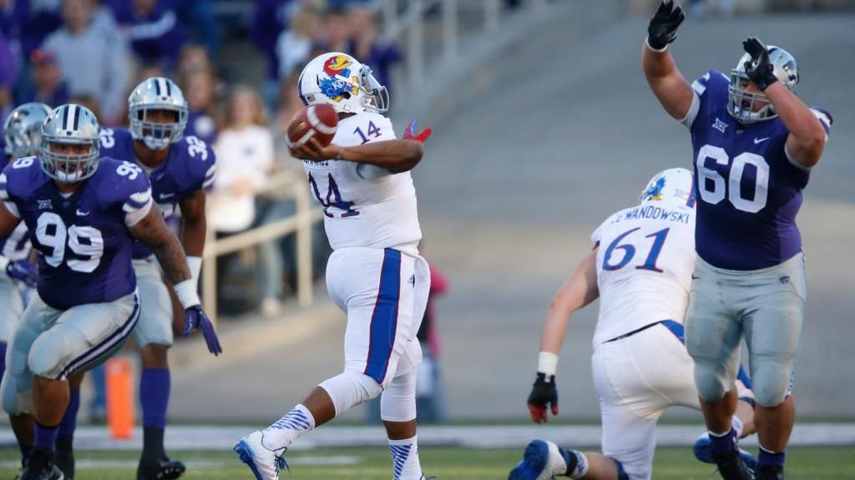 Despite coverage by K-State defensive tackle Will Geary (60) charges at the quarterback against Kansas.(November 29, 2014)