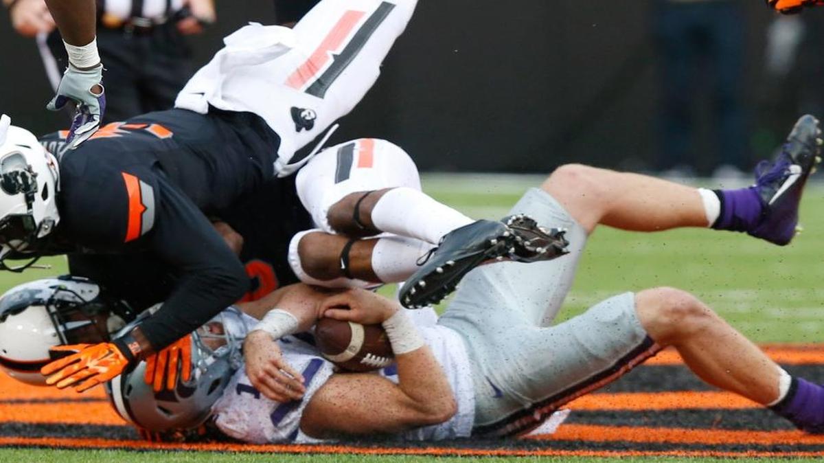 
K-State quarterback Kody Cook is slammed to the turf by a pair of Oklahoma State players during Saturday’s game. 
