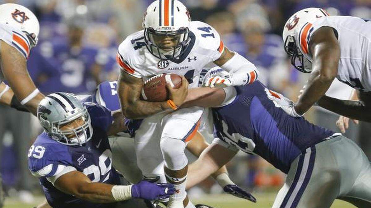 
Auburn quarterback Nick Marshall runs up field while K-State defensive tackle Valentino Coleman, left, and defensive lineman Travis Britz make the tackle.
