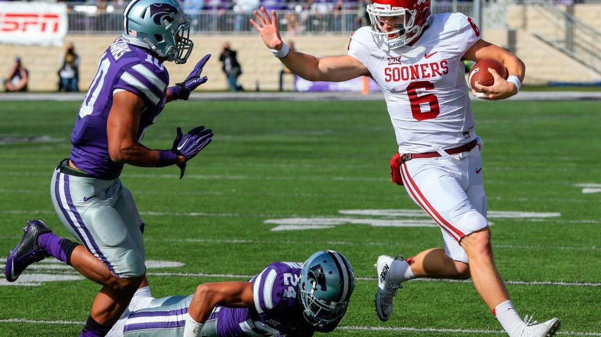 Oklahoma quarterback Baker Mayfield runs away from Kansas State defensive backs Nate Jackson, bottom, and Donnie Starks on Saturday.