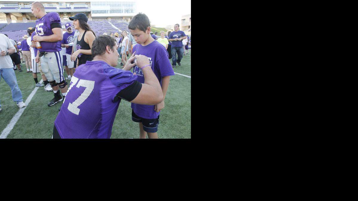 
Offensive lineman Boston Stiverson signs a young fan’s shirt at a public practice Aug. 17 in Manhattan.
