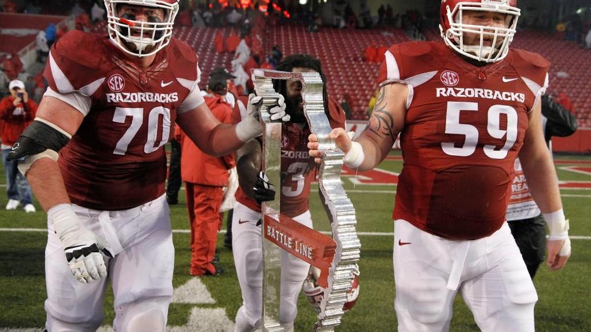 Arkansas’ Dan Skipper (70), Alex Collins (3) and Marcus Danenhauer (59) push the Battle Line trophy off the field after Arkansas beat Missouri in November.