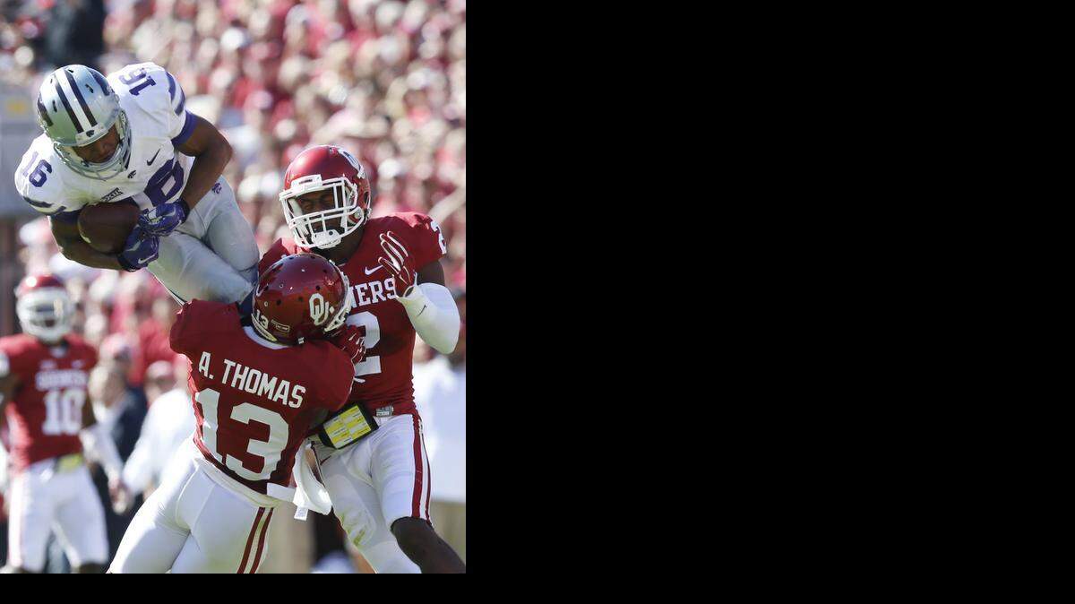 
K-State wide receiver Tyler Lockett (16) hauls in a Jake Waters (15) pass early in the 3rd quarter as Oklahoma safety Ahmad Thomas (13) defends on the play.(October 18, 2014) 
