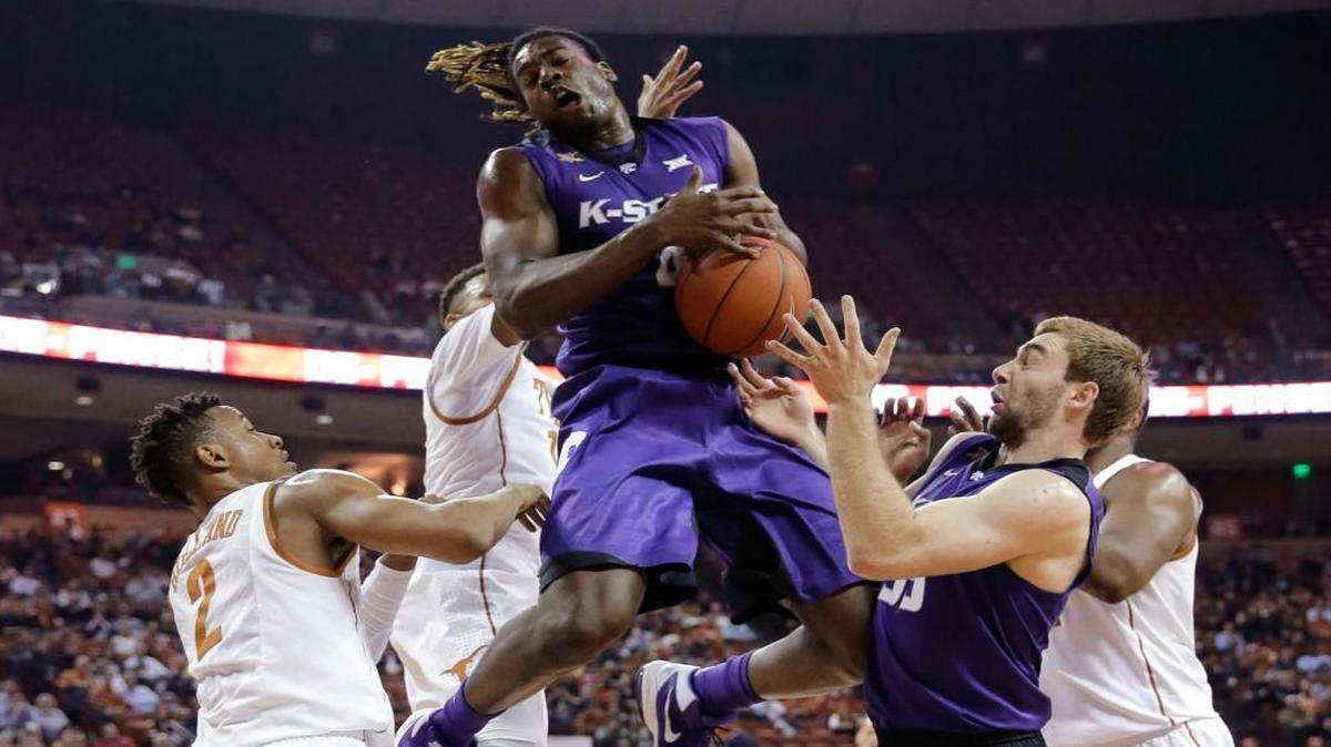 Kansas State forward D.J. Johnson pulls down a rebound over Texas guard Demarcus Holland, left, during the first half Tuesday in Austin.