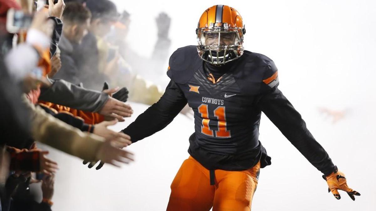 Oklahoma State safety Tre Roberts slaps hands with fans as he runs out onto the field before Saturday’s game against Baylor.