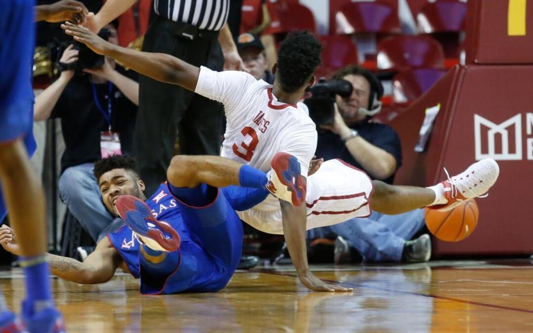 Kansas guard Frank Mason, left, and Oklahoma guard Christian James tumble to the court during the first half Tuesday in Norman.