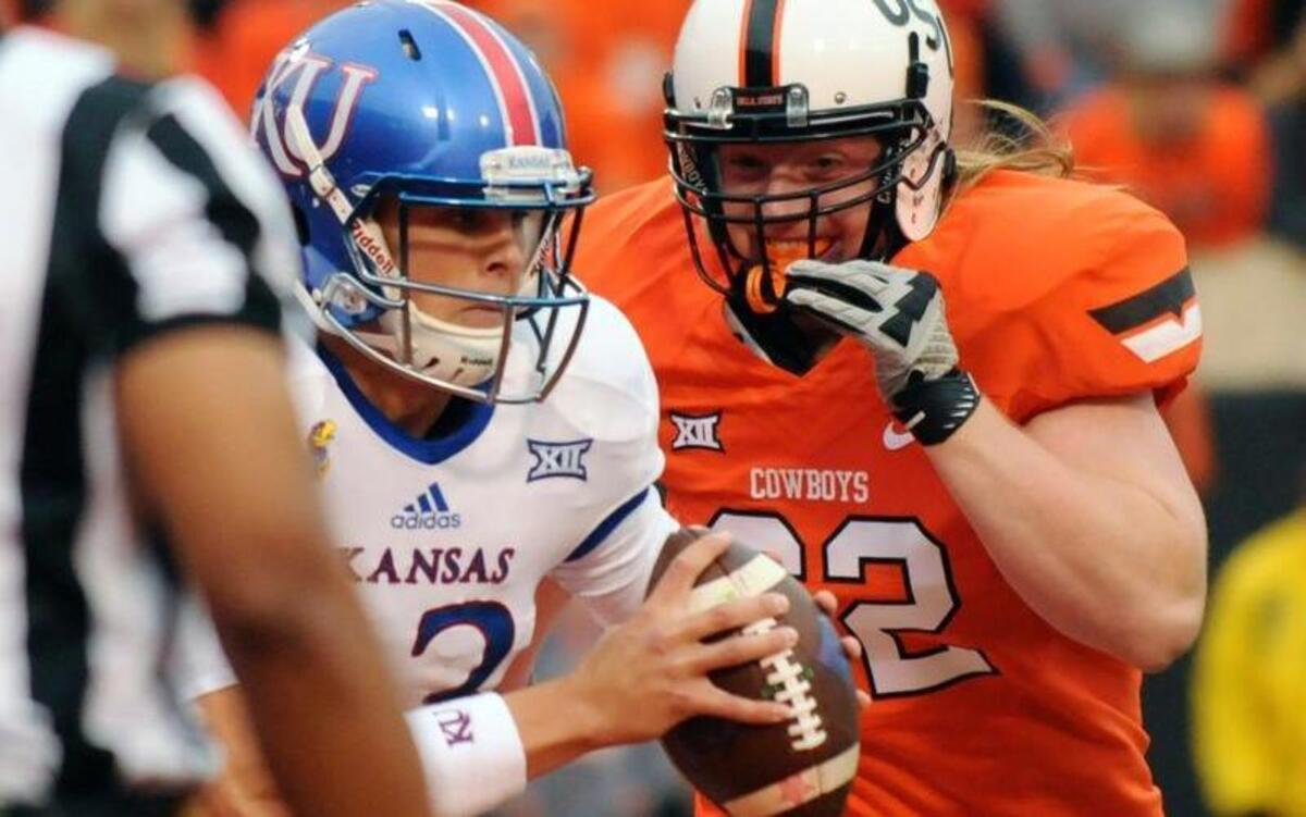 Oklahoma State defensive tackle Tyler Ferguson, right, sacks Kansas quarterback Ryan Willis during the fourth quarter Saturday in Stillwater, Okla.