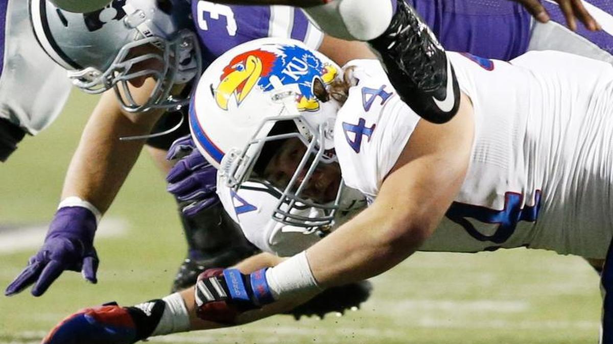 K-State running back Jarvis Leverett Jr. is tripped up by Kansas’ Michael Zunica late in their 2014 game in Manhattan.