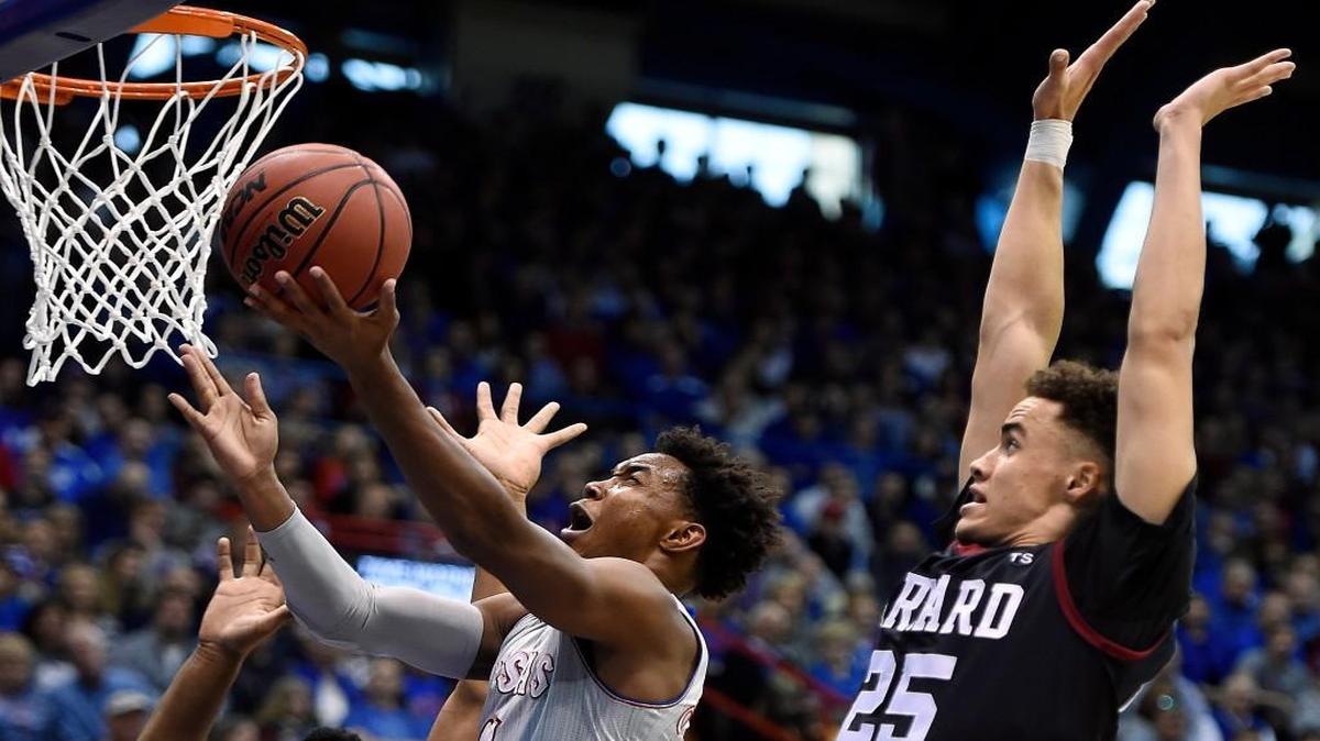 KU’s Devonte Graham drives between Harvard defenders Zena Edosomwan, left, and Corey Johnson during the first half of Saturday’s game at Allen Fieldhouse.