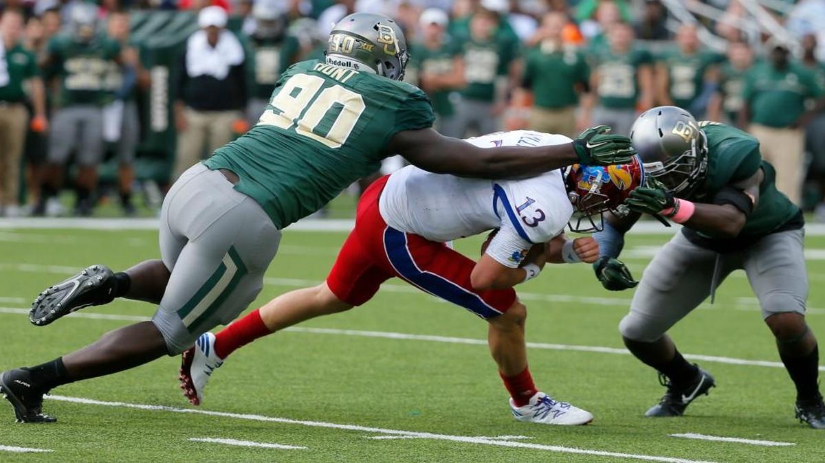 Kansas quarterback Ryan Willis is tackled by Baylor’s Tyrone Hunt (90) and Raaquan Davis on Saturday in Waco, Texas.