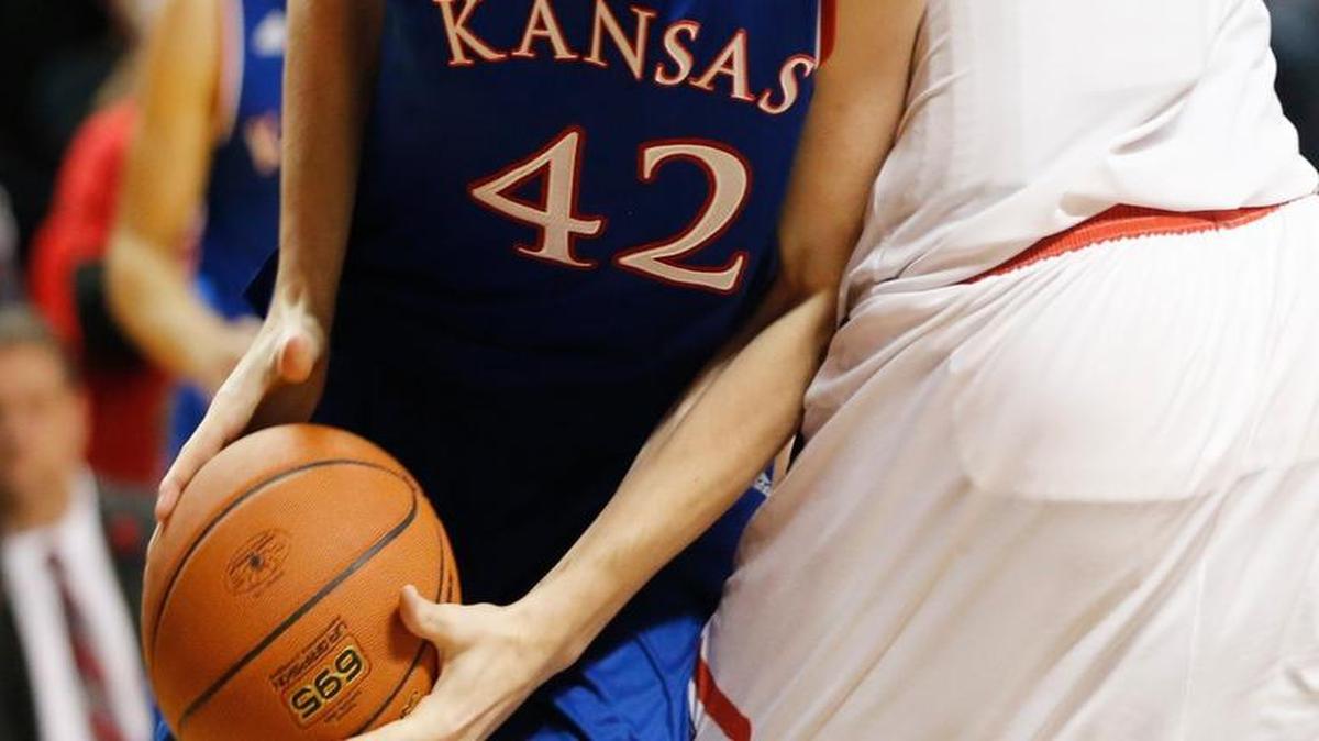 Kansas forward Hunter Mickelson, left, drives under Texas Tech center Norense Odiase in the first half Saturday.