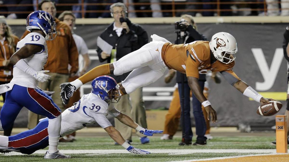 Texas quarterback Tyrone Swoopes (18) dives for a touchdown as Kansas defendersTyrone Miller Jr. (19) and Michael Glatczak chase him during the second half Saturday in Austin.