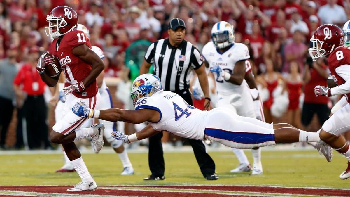 Oklahoma wide receiver Dede Westbrook scores a touchdown as Kansas defensive end Cameron Rosser tries to make a diving tackle during the first half Saturday in Norman, Okla.