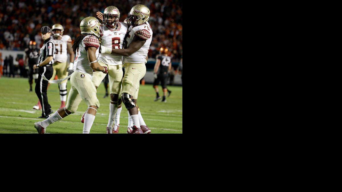 
Florida State defensive back Jalen Ramsey is congratulated by offensive tackle Cameron Erving after intercepting a pass thrown by Miami quarterback Brad Kaaya in the second half an NCAA college football game, Saturday, Nov. 15, 2014, in Miami Gardens, Fla. Florida State defeated Miami 30-26. 
