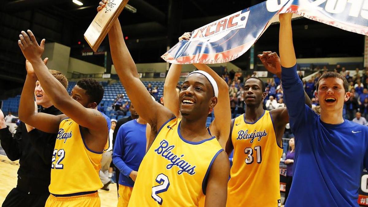 Tabor's D'Marco Smith holds the championship plaque aloft as he acknowledges the Blue Jays' fans after beating Southwestern 75-68 in the KCAC men's final Monday night at Hartman Arena.