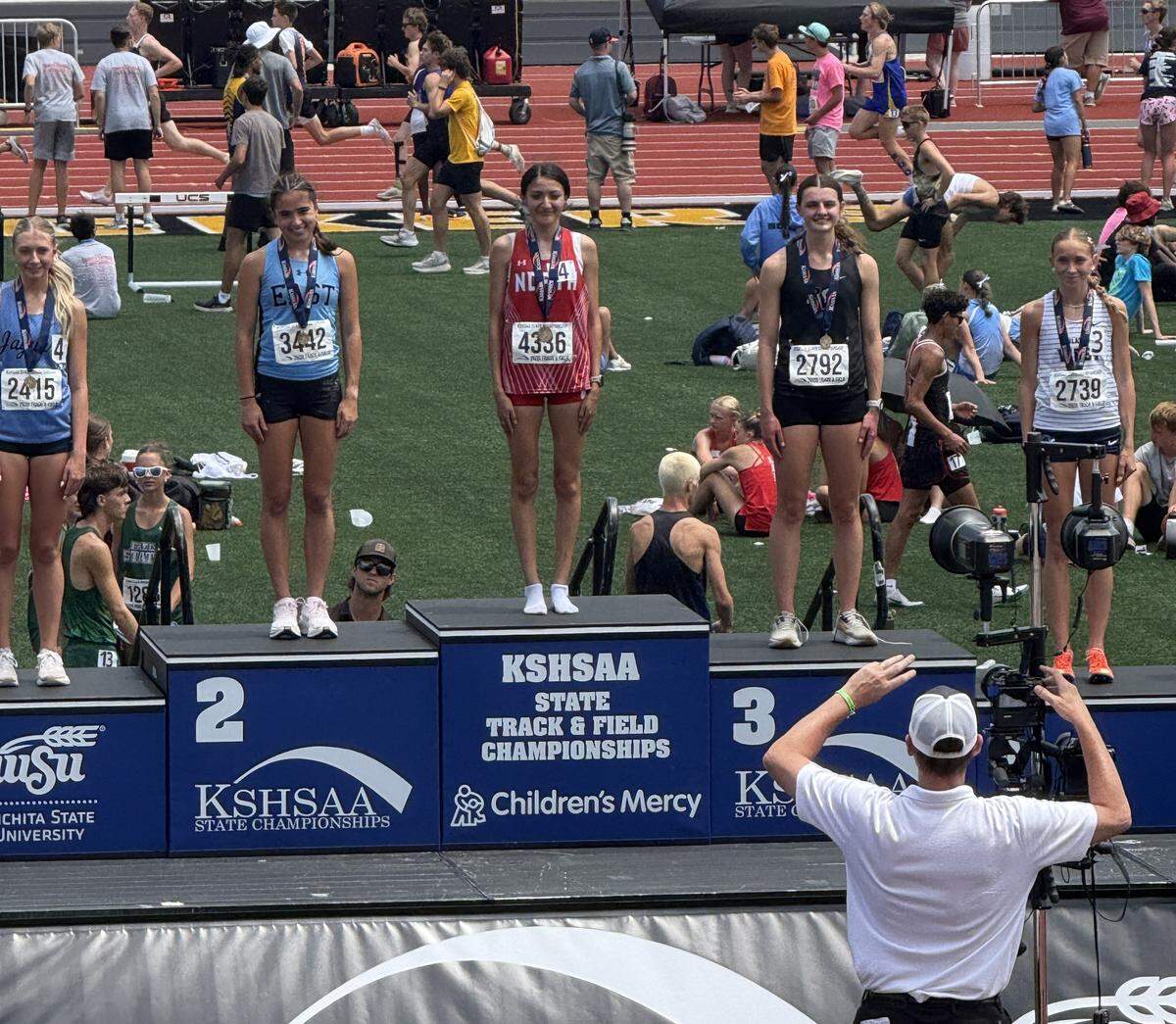 Wichita North senior Nelly Puente stands atop the Class 6A girls 1600-meter podium to receive her first-place medal after winning a Kansas high school state track title Saturday at Crossland Stadium.