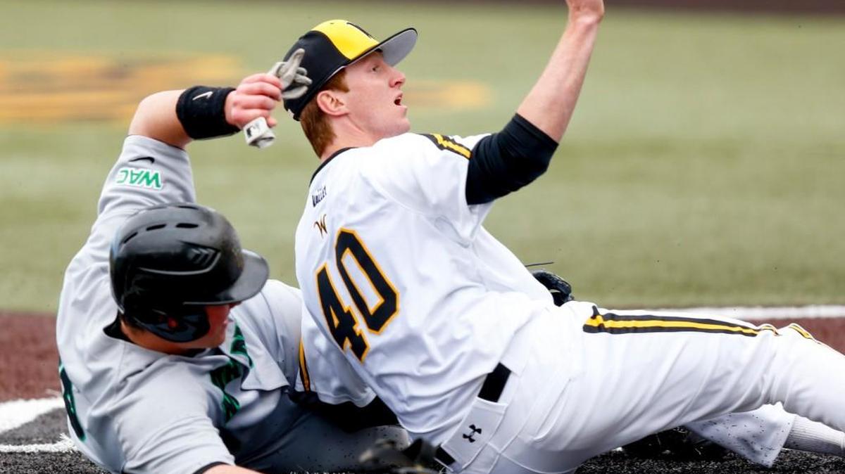 Wichita State pitcher Clayton McGinness holds up the ball for the umpire after tagging out North Dakota's Brett Harrison, left, after Harrison tried to score in the second inning.