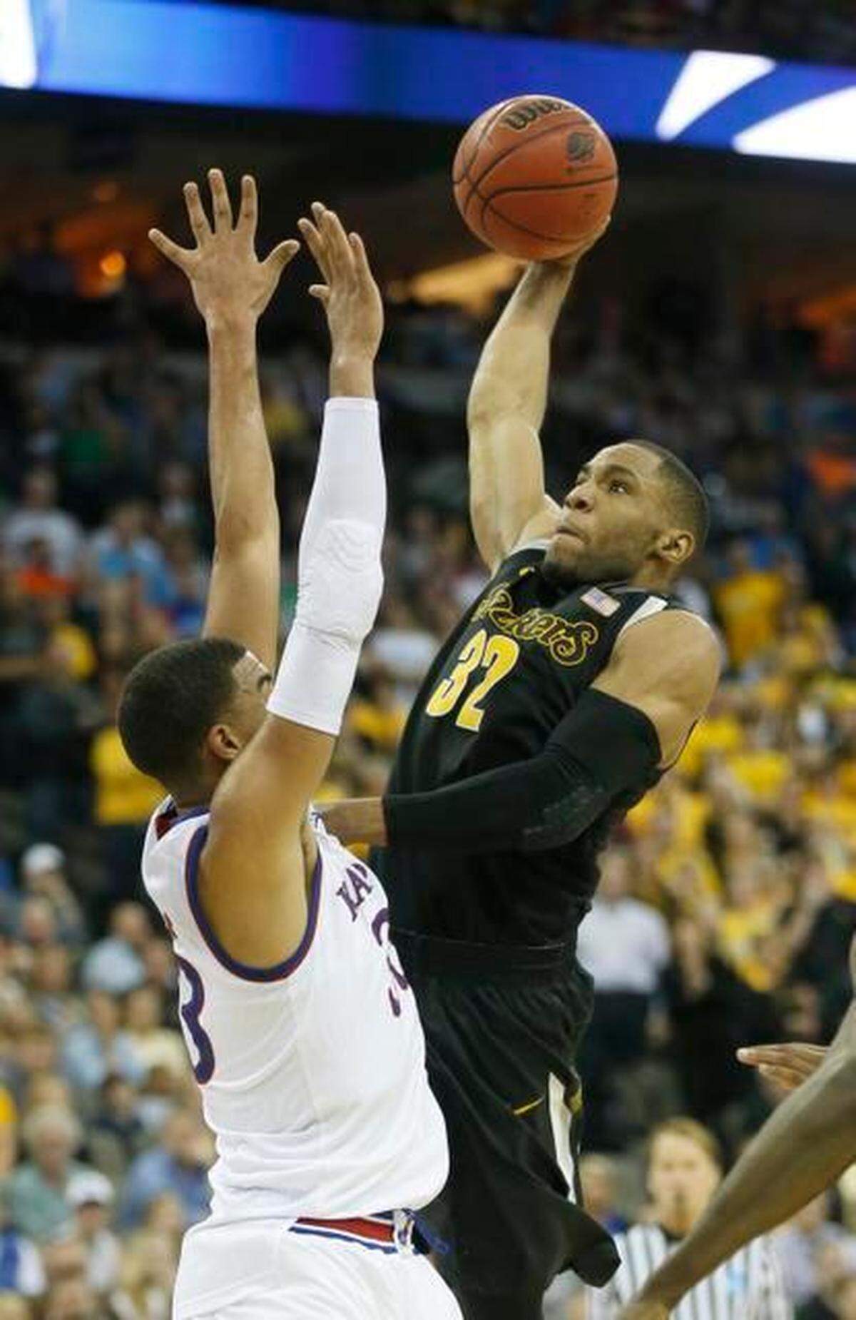 Wichita State guard Tekele Cotton dunks over Kansas forward Landen Lucas in the first half of their game in the NCAA Tournament at CenturyLink Center in Omaha. He was fouled on the play and the basket was good. 