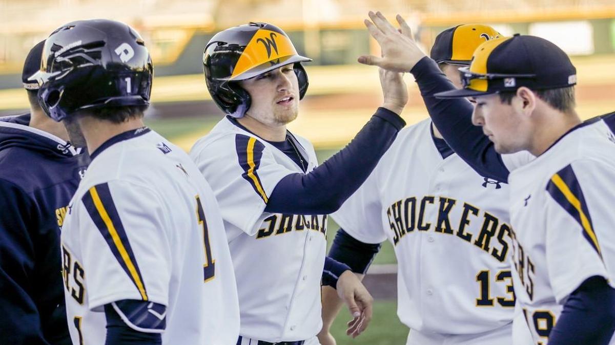 Wichita State teammates greet Mikel Micha after he scored the Shockers’ first run in the fourth inning Tuesday at Eck Stadium.