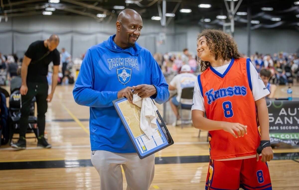 Tyrone Berry shares a laugh with a Team PE 34 player during a summer tournament game, a small glimpse of why he has become such a beloved figure in the Wichita basketball community.