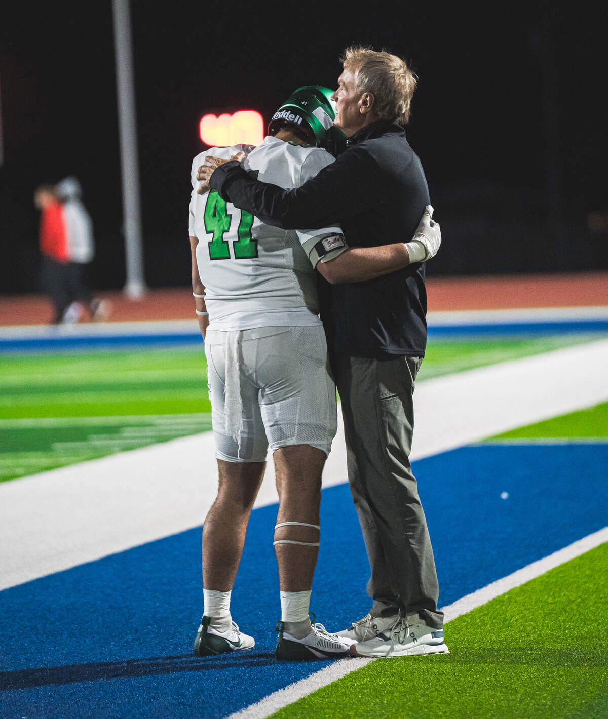 Derby football character coach Kevin Chase is considered a father figure to many of the players on the team. He hugs junior linebacker Mason Moaliitele before Derby’s 63-21 win over Northwest last week.