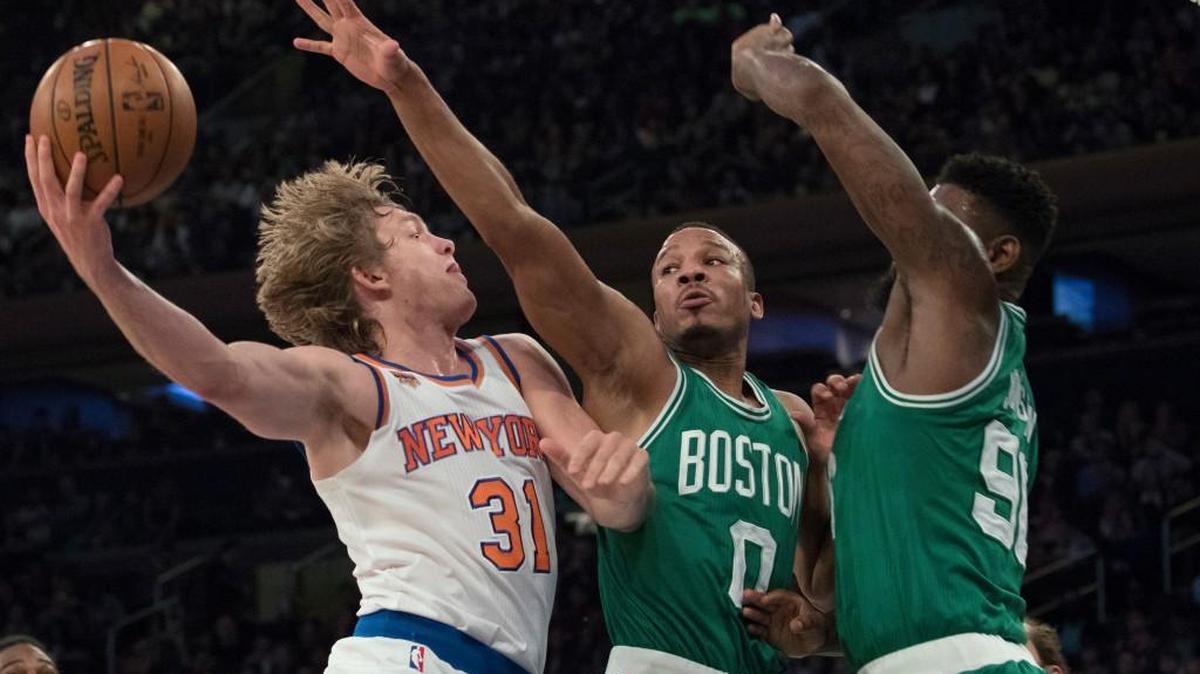 New York Knicks guard Ron Baker (31) goes to the basket against Boston Celtics forward Amir Johnson (90) and guard Avery Bradley (0) during the first half of a preseason NBA basketball game.